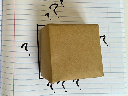 a bar of soap wrapped in brown paper surrounded by question marks